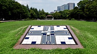 Worlds first solar clock built in 1983, located in Hibiya Park, Japan. Tile clock in a field of grass with Solar panels located perpendicular of each other, going towards 12 o'clock, 6 o'clock, 3 o'clock and 9 o'clock. The clock hands move every minute with energy provided from the sun. This was built to help with sustainable engineering and the environment.