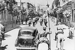 The fall of Damascus to the Allies, late June 1941. A car carrying Free French commanders General Georges Catroux and General Paul Louis Le Gentilhomme enters the city, escorted by French Circassian cavalry (Gardes tcherkesses).