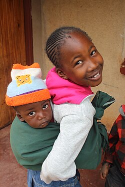 A sister (female sibling) carrying her brother (male sibling).