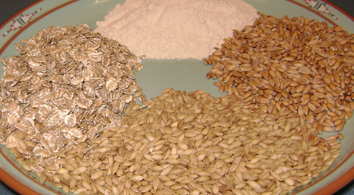 4 different commercial forms of Triticeae cultivars. Clockwise from top: common wheat flour, European spelt, barley corns, rolled rye