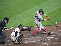 Boston Red Sox player Mookie Betts hits a pitch by swinging his bat.