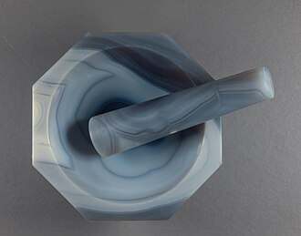 An agate mortar and pestle is used to finely grind vitreous enamel powder, mixed with a volatile oil, such as lavender oil, to produce enamel paints for artistic work.