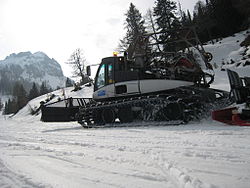 An Italian snowcat with grooming blade hauling a roller