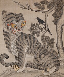 A vertical painting in watercolor on paper with primarily black, white, and gray tones. It depicts a stylized tiger with a humorous, exaggerated expression and yellow eyes sitting at the bottom and looking up toward a magpie perched on the branch of a gnarled pine tree above.