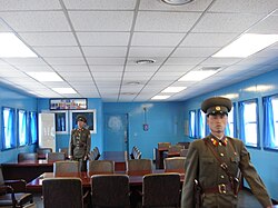 Two KPA soldiers standing guard inside a JSA conference room, in front of the door leading to the South Korean side of the JSA. View from north to south.