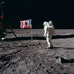 Apollo 11 astronaut Buzz Aldrin, Apollo Lunar Module pilot of the first crewed mission to land on the Moon, poses for a photograph beside the deployed United States flag during his Extravehicular Activity (EVA) on the lunar surface.