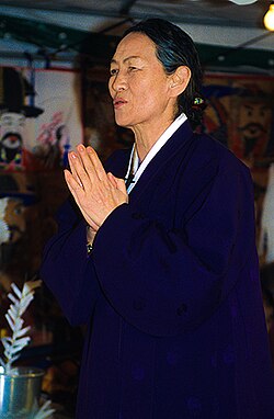 A woman dressed in black with her palms pressed together