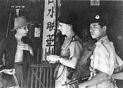 Malayan police officers questioning an ethnic Chinese civilian during the Malayan Emergency in 1949