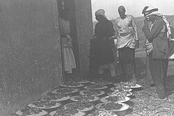 Servants waiting to serve bowls of rice and roast lamb to guests attending an Arab farmer's wedding in the Negev, 1933.