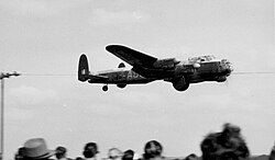 An Avro Lancaster B.VII modified for the film with cut-out bomb bay and mock bouncing bomb demonstrating to a crowd at Coventry Airport in 1954