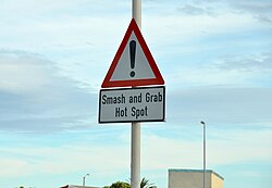 Sign warning motorists about the prevalence of smash and grab incidents at a "Crime Hot Spot" on the M5 freeway, between the lower-income neighbourhoods of Grassy Park and Retreat, situated in the Cape Flats region of the city