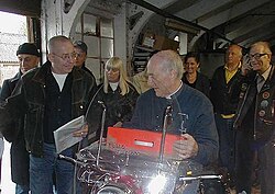 Len Paterson, founder of the Rocker Reunion movement, left, Father Graham Hullet of the 59 Club, seated on motorcycle, at Enfield Motorcycles factory, UK.