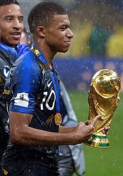Mbappé holding the FIFA World Cup Trophy after France won the 2018 World Cup final