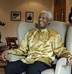 Mandela on a visit to Australia in 2009; he is wearing one of the brightly coloured garments that became known as "Madiba shirts".