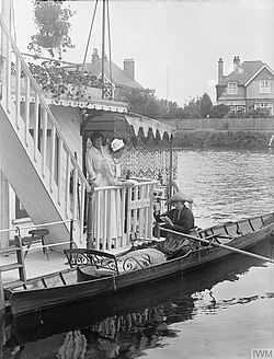 A letter carrier delivering mail by boat to a houseboat during World War I