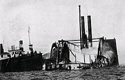 A steamboat on fire: General Slocum, a New York City sidewheeler, still burning after a fire that killed more than 1,000 people