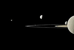 Five moons in a Cassini image: Rhea bisected in the far-right foreground, Mimas behind it, bright Enceladus above and beyond the rings, Pandora eclipsed by the F Ring, and Janus off to the left