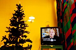 A television screen shows King Harald V of Norway addressing the Norwegian people.