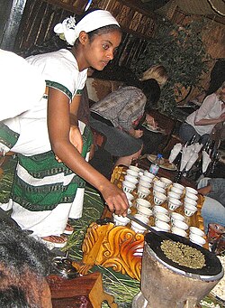 An Ethiopian woman preparing Ethiopian coffee at a traditional ceremony. She roasts, crushes, and brews the coffee on the spot.