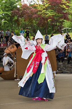 A person wearing flowing clothes with arms raised