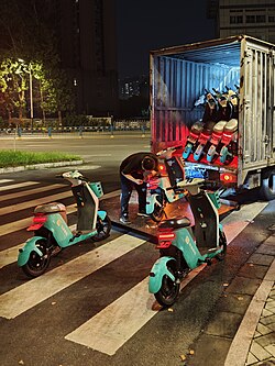 Shared-use electric bicycles being maintained by company staff at late night