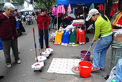 A market trader demonstrating a mop to potential customers