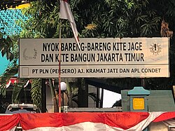 A sign encouraging development in East Jakarta written in the Betawi language