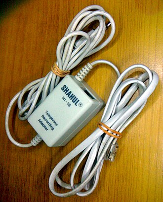 A telephone recording adapter (in-line tap). The phone jack connects to the wall socket while the phone being monitored is connected to the adapter's socket. The audio plug connects to the recording device (computer, tape recorder, etc.).