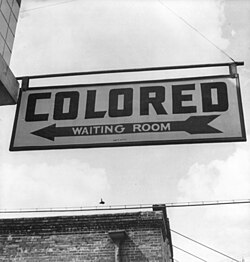Sign for "colored" waiting room at a Greyhound bus terminal in Rome, Georgia, 1943. Throughout the Southern United States there were Jim Crow laws creating de jure legally required segregation.