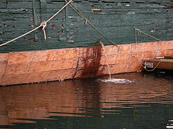 A ship pumping bilge water into a harbor