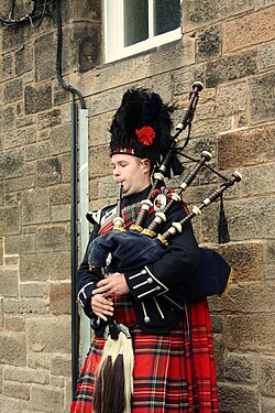 A bagpiper busking with the Great Highland bagpipe on the street in Edinburgh, Scotland