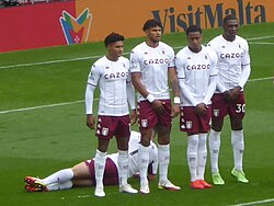 Aston Villa players have a man lying on the ground behind the wall to stop low free kicks