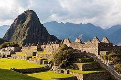 Terraced slopes and stone buildings of Machu Picchu with surrounding Andean mountains.