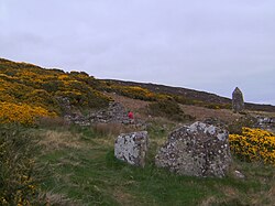 Ruins of the Badbea longhouses with the 1911 monument in the background