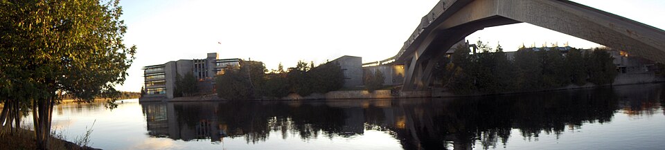 Trent University; a view across the Otonabee River, showing the west bank part of the campus, including Bata Library on the left. The Faryon bridge is to the right.
