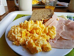 Scrambled eggs served with ham and toast