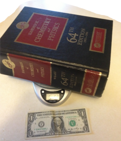 64th Edition of CRC Handbook of Chemistry and Physics with an American dollar bill for scale; weighs 6 pounds 5.0 ounces (2.86 kg)