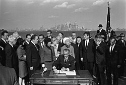 President Johnson signs the Immigration and Nationality Act of 1965 as U.S. Senators Edward Kennedy and Robert F. Kennedy, and others look on.