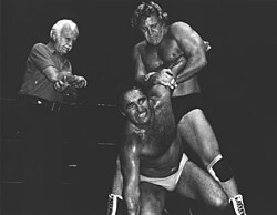 Tommy Seigler applies a hold to Nick Kozak while a referee looks on.