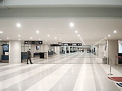 Inside the airport, with passenger check-in and the entrance to passport control out of frame to the right