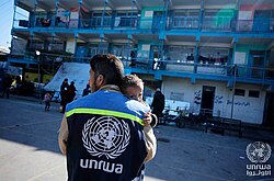 UNRWA staff member comforts a distressed child at a school shelter in Nuseirat camp, Gaza Strip.