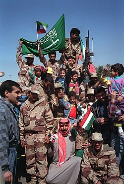 Civilians and coalition military forces wave Kuwaiti and Saudi Arabian flags as they celebrate the retreat of Iraqi forces from Kuwait.