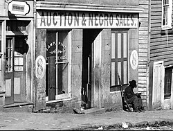 George N. Barnard's photograph of a slave trader's business on Whitehall Street Atlanta, Georgia, 1864. A United States Colored Troop Infantry corporal is sitting by the door.