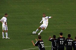 David Beckham (centre) scoring with a bending free kick in 2007. The ball is struck with the inside of his right foot, with his body leaning to the left to generate extra curl on the ball.