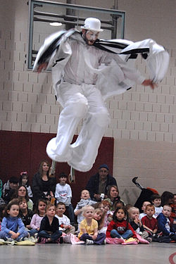 Children entertained by a stilt walker performing in a circus act