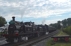 British Railways Class A1X Terrier No. 32662, No. 32678 and No. 32670 triple head a passenger train at Bodiam on the Kent and East Sussex Railway.