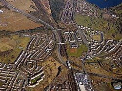 Aerial view of the M80 motorway looking east at Provanmill as it passes under the Cumbernauld Line railway tracks and the B765 Robroyston Road (2018)