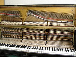 The mechanism and strings in upright pianos are perpendicular to the keys. The cover for the strings is removed for this photo.