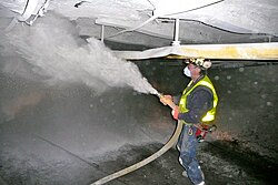 A coal miner in West Virginia spraying rock dust to reduce the combustible fraction of coal dust in the air