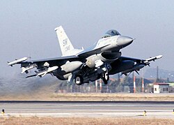 Jet heavily armed with weapons under wings taking off.